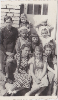 Danuta Neuhüttler (środek pierwszego rzędu) z rodziną i przyjaciółmi. ul. Wołodyjowskiego 13, Białystok, ok. 1943 r.