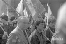 Pochód z okazji świięta 1 Maja, mężczyźni z transparentami i flagami, Aleja 1 Maja (obecnie Józefa Piłsudskiego), Białystok, druga połowa lat 70. XX w., fot. ze zbiorów Andrzej Trzcińskiego