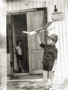 Portret chłopca z modelem przed wejściem do niestniejącej Młodzieżowej Modelarnii Lotnicznej, ul. Mazowiecka, Białystok, lata 60. XX w.