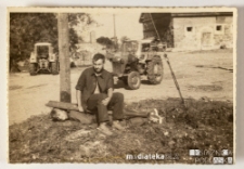 Dwóch chłopców strojących sobie żarty, w tle podwórko i maszyny gospodarcze, PGR Kociołek, 1973 r.