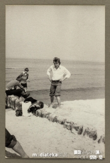 Uczniowie z opiekunem przy drewnianych palach na brzegu morza, Ustka, 1979 r.