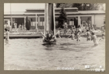 Człowiek wpadający ze zjeżdżalni do odkrytego basenu