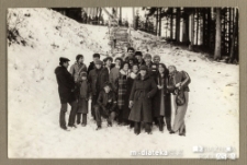 Grupa ludzi pozująca na tle ośnieżonej skarpy w lesie