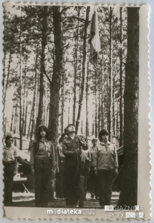 Harcerze w umundurowaniu zawieszają chorągiew