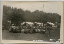 Harcerze siedzący w kręgu w obozie