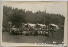 Harcerze siedzący w kręgu w obozie