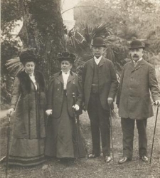 Dwie kobiety w długich sukniach i kapeluszach i dwóch mężczyzn w melonikach