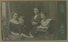 Cztery młode kobiety w długich sukniach, siedzące w atelier, dwie jednakowo ubrane