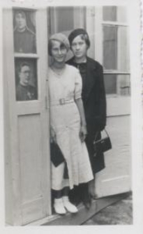 Dwie młode kobiety w drzwiach, na szybie obrazki duchownych