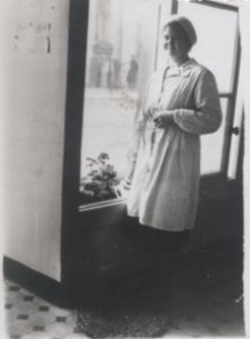 Sprzedawczyni w białym fartuchu i czapce przy oknie wystawowym w sklepie