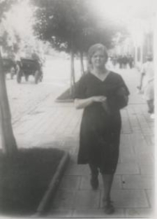 Młoda kobieta w ciemnej sukni idąca ulicą