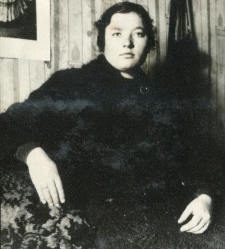 Kobieta w ciemnym ubraniu siedzi na boku kanapy