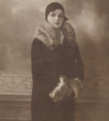 Kobieta w długiej sukni stoi przy kwietniku w atelier fotograficznym